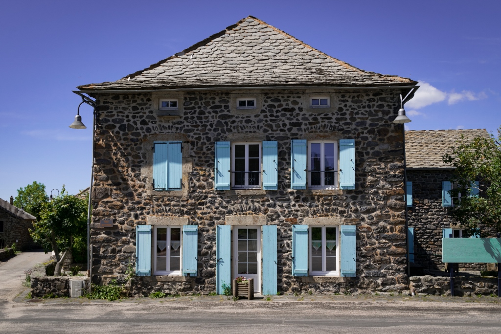 Vue sur une maison en pierre avec volets bleus au village de Moudeyres en Haute-Loire