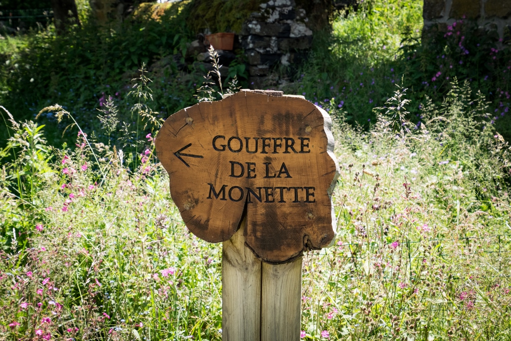 Vue sur panneau en rondin de bois avec inscription Gouffre de la Monette